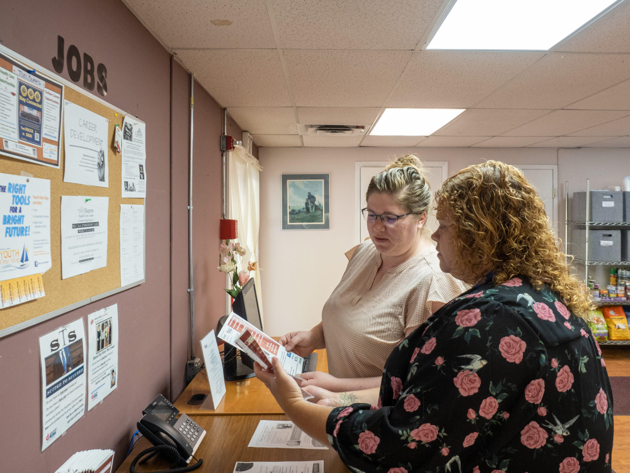 Two staff members of CAPDC in discussion by a bulletin board.