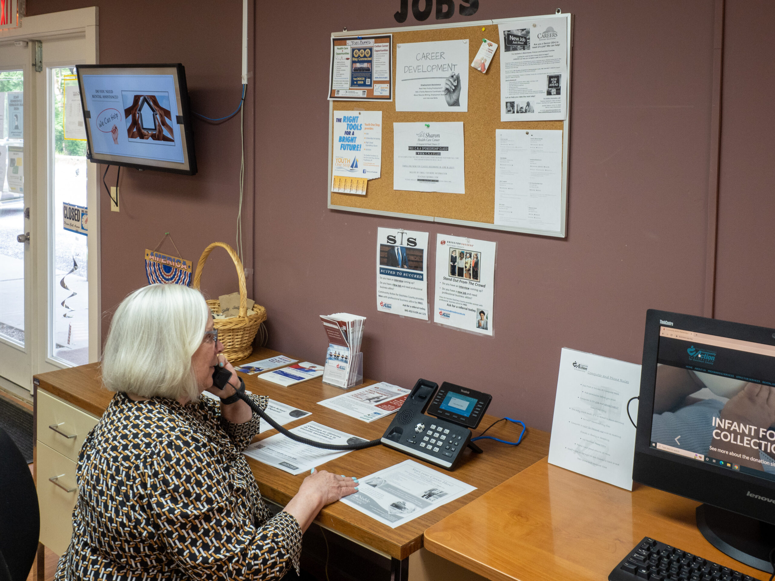 CEO of Community Action Partnership of Dutchess County sitting at a desk while speaking with a client on the phone.