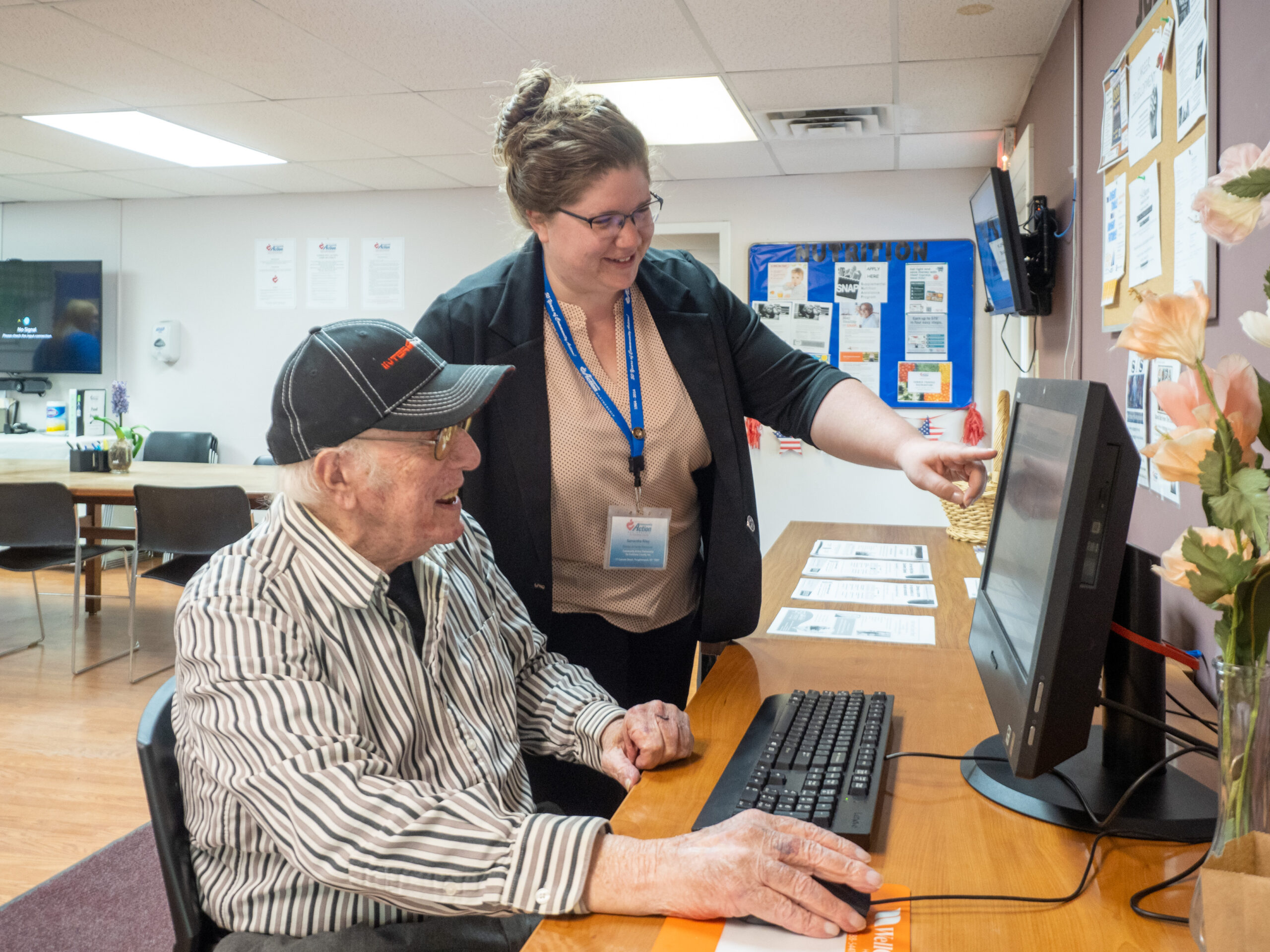 A staff member of Community Action Partnership of Dutchess County helps an elderly client use the computer.